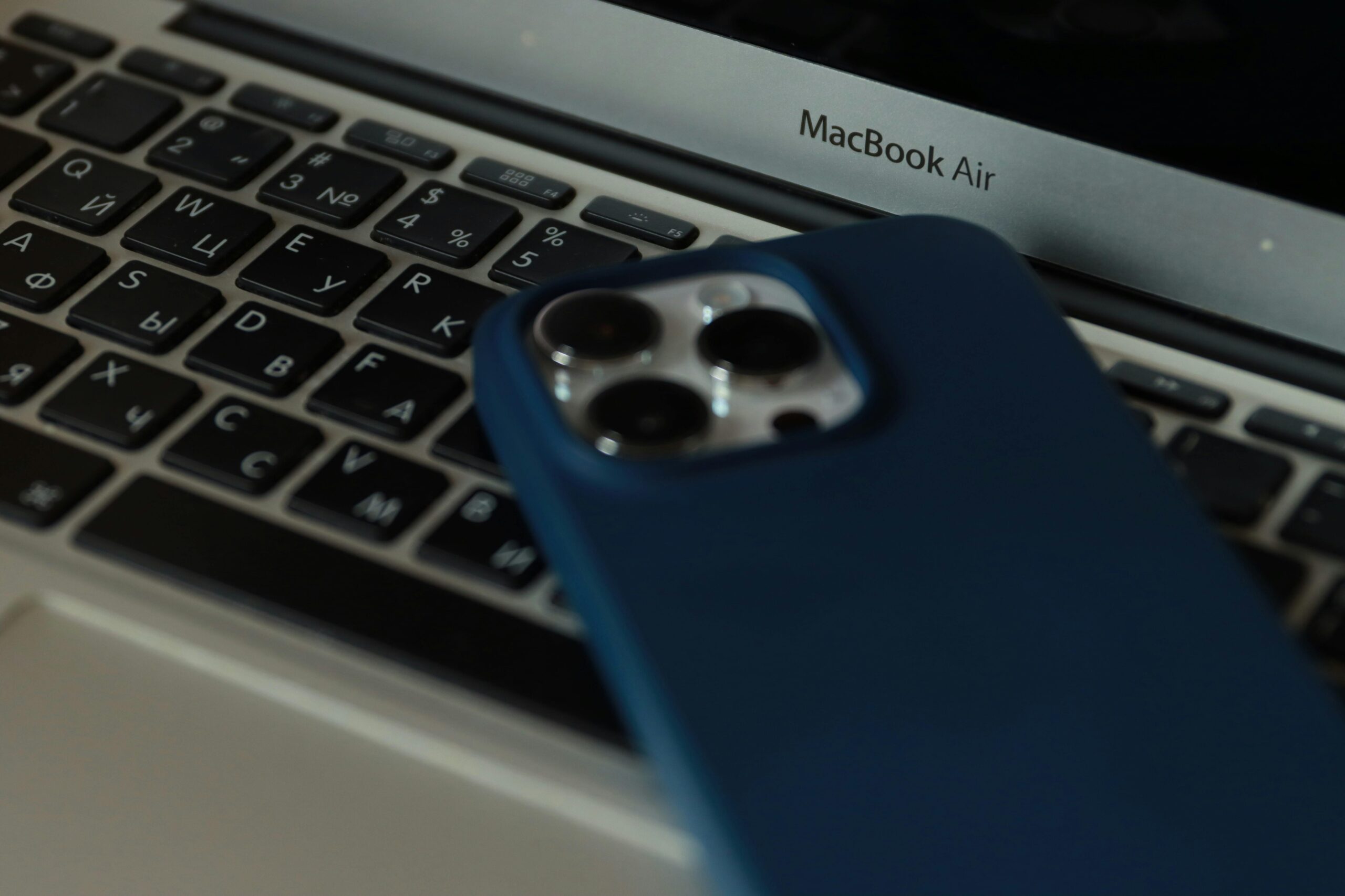 A close-up of a MacBook Air and an iPhone, showcasing modern technology in an office setting.